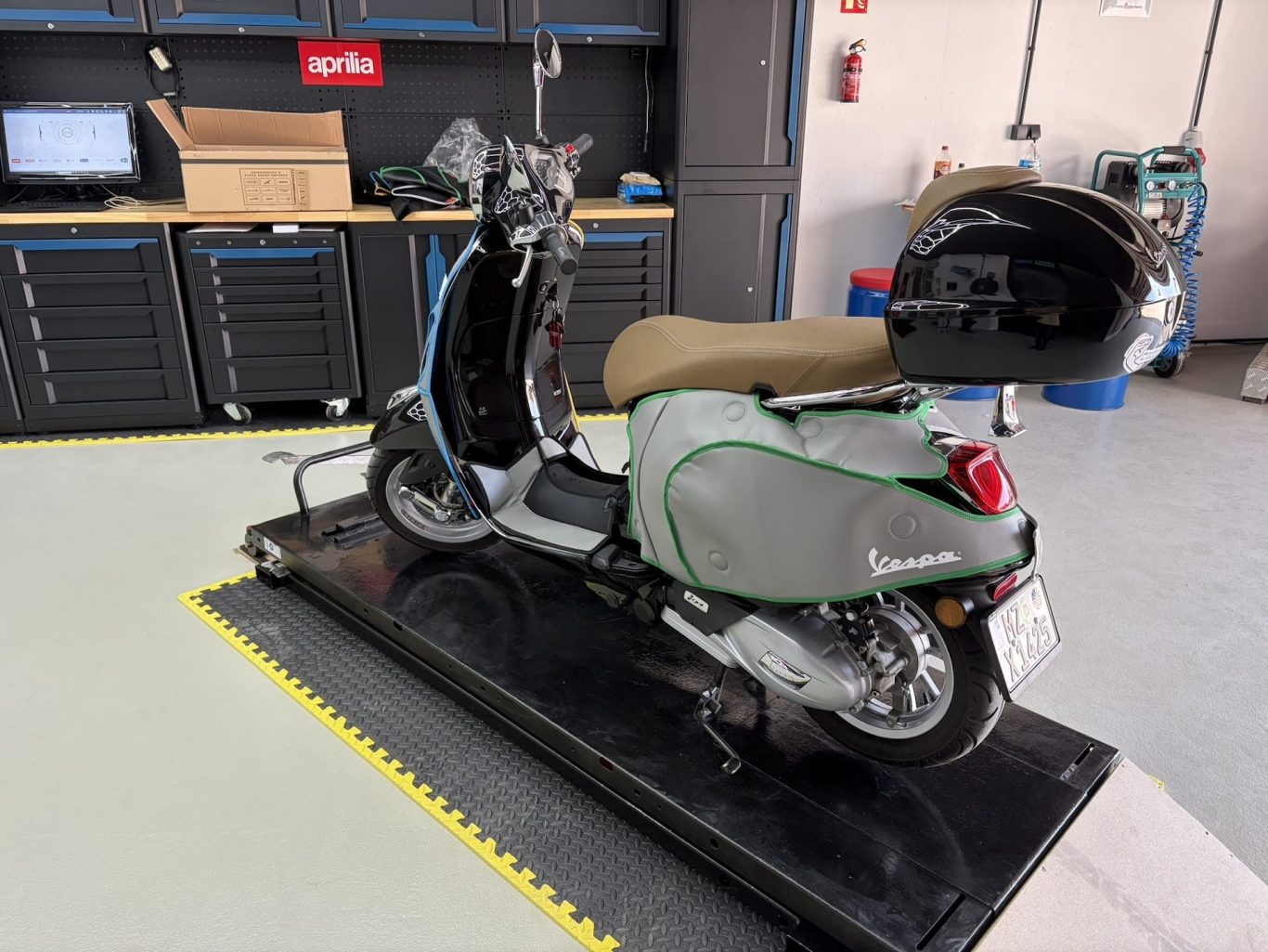 Vespa auf Hebebühne mit Schutzabdeckung und Topcase in professioneller Rollerwerkstatt