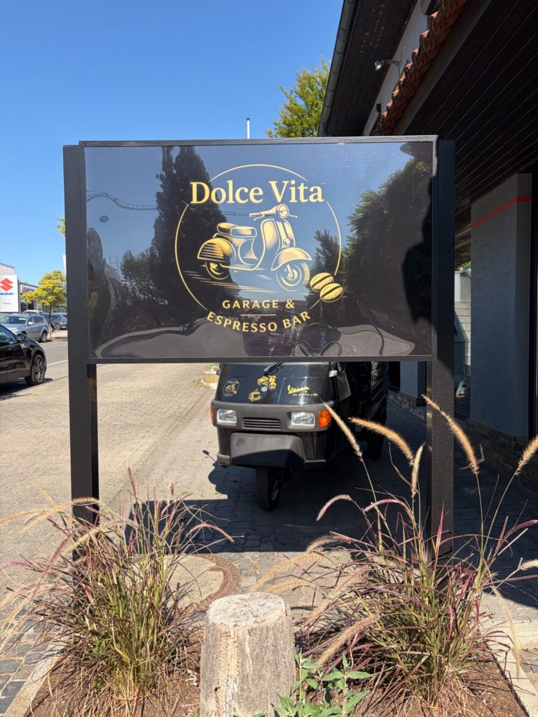 Dolce Vita Garage & Espresso Bar mit Logo auf schwarzem Außenschild